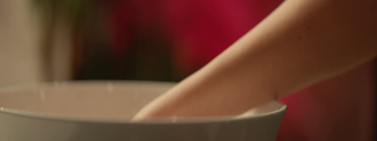 A woman puts her hand into a bowl of water