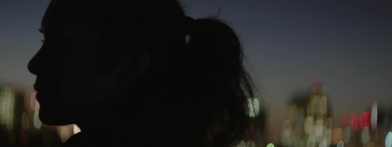 A woman stands outside in a city at night