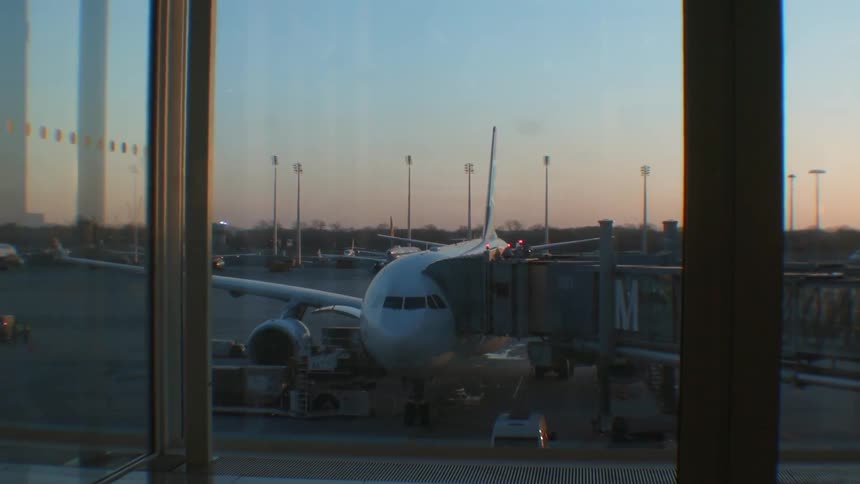 Airplane at its gate with the passenger tunnel attached at sunset