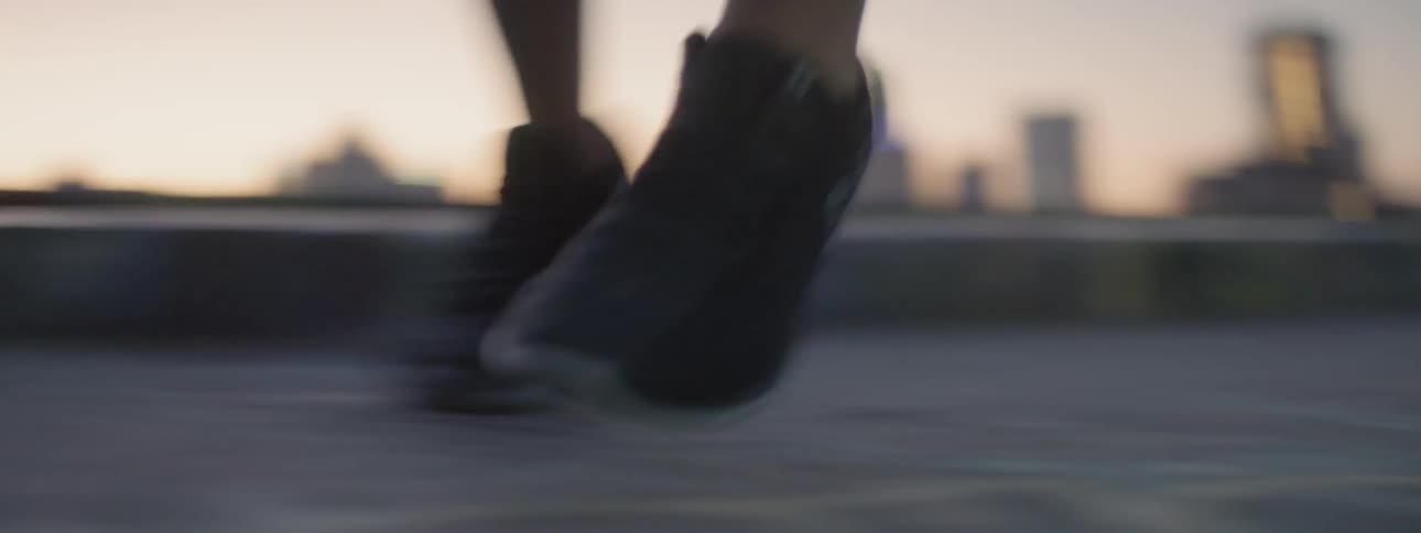 A woman exercises in a city at sunset