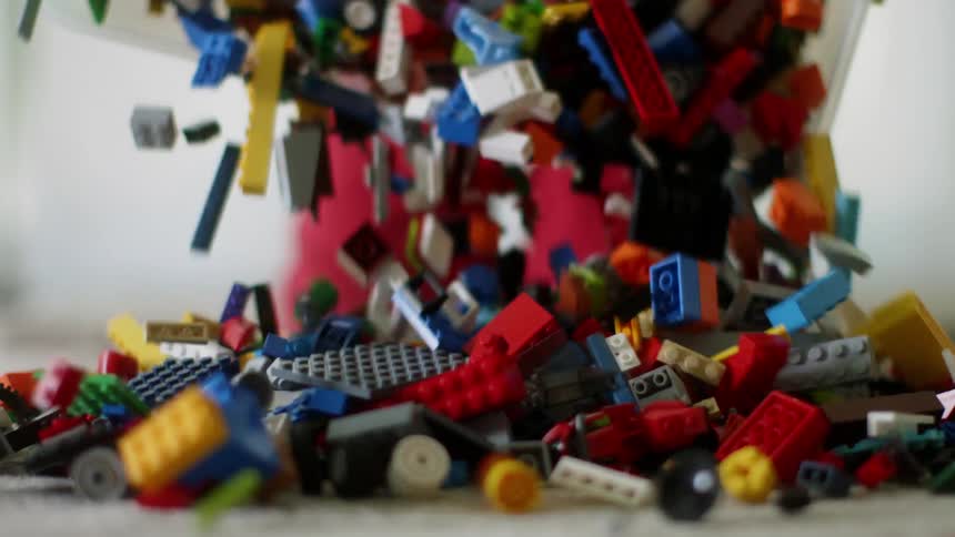 A bin of toy building blocks is dumped on the floor