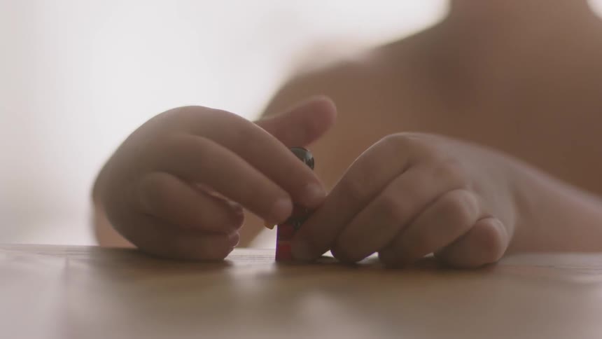 A child is playing with a building block character in a room in daylight