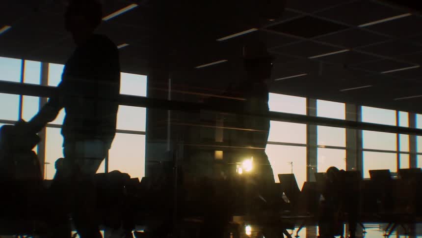 Travelers sit in an airport terminal at sunset