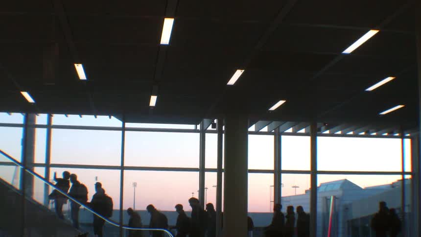 Travelers ride up an escalator in an airport