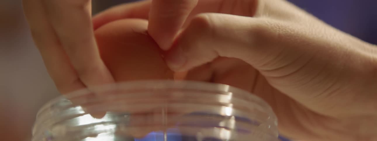 Woman cracking open an egg and pouring it in a jar