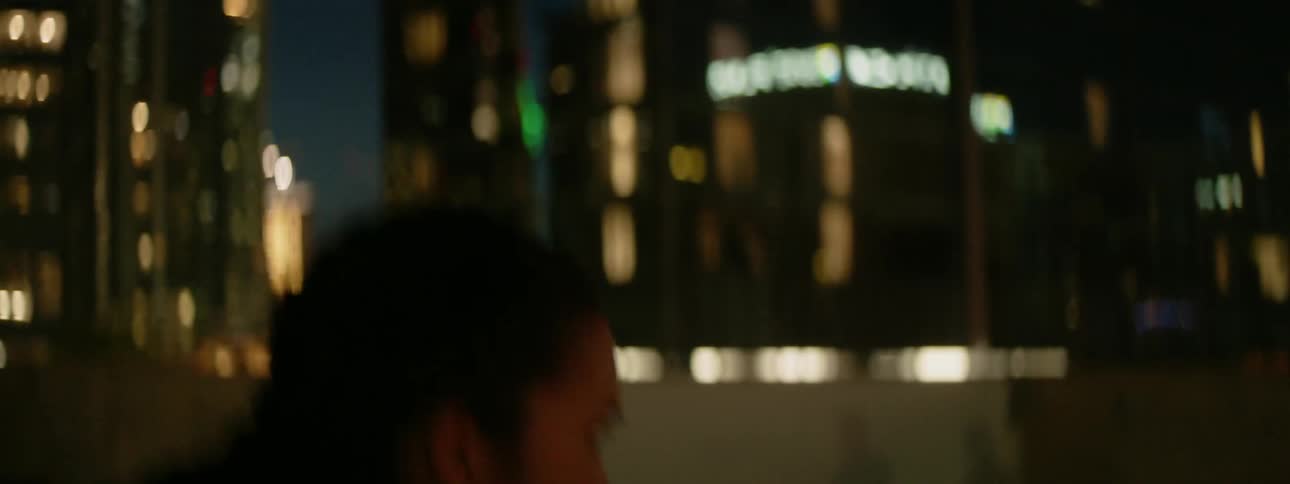 A woman shadow boxes on a rooftop at night