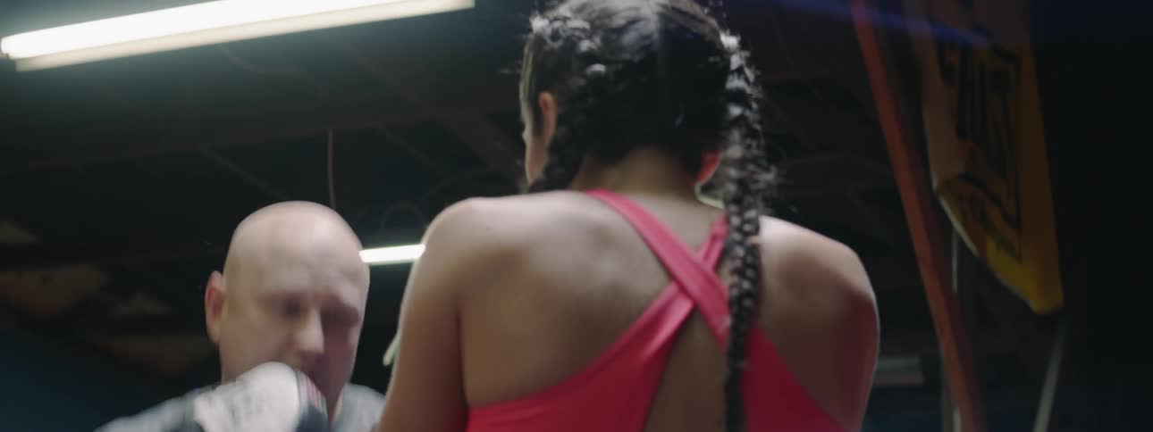 A woman is practicing her boxing technique with her coach