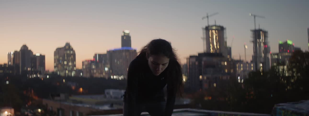 A woman exhales while leaning over on a rooftop