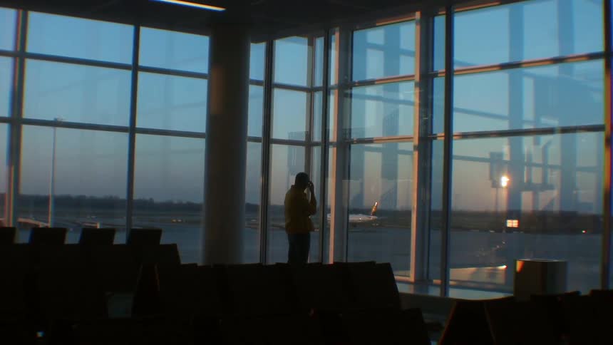 Man stands in airport looking out window
