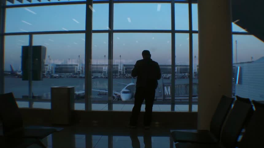 Man standing near the windows at an airport gate area