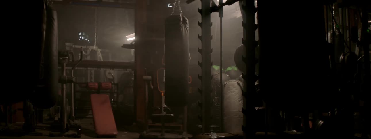 A heavy bag sways in a gym as the lights turn off