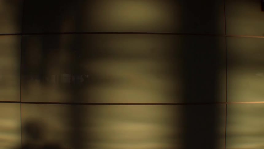 Shadows are cast on a wall as people walk by