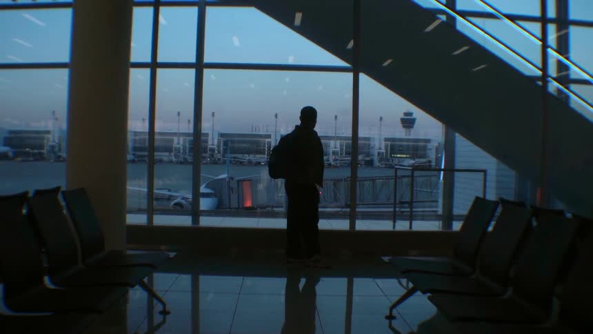 A man looks out the window towards the runway