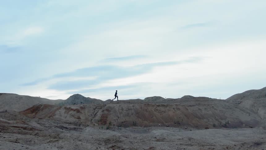 A person walks on sandy hilly land