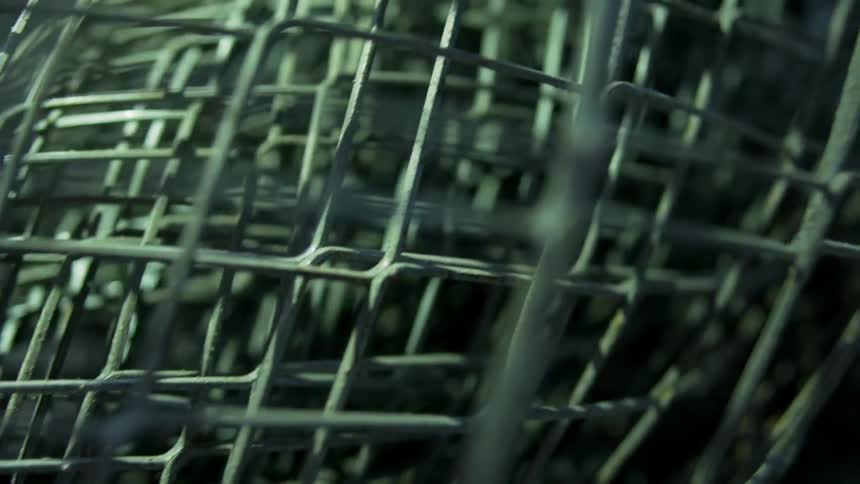 Shadow and light is moving across a roll of chain link fence