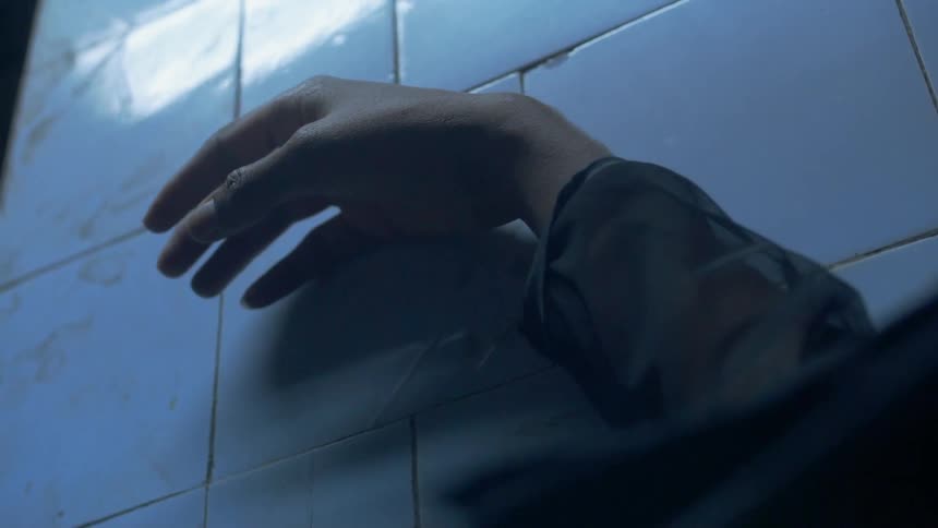 A man rubs his arm against a tile wall