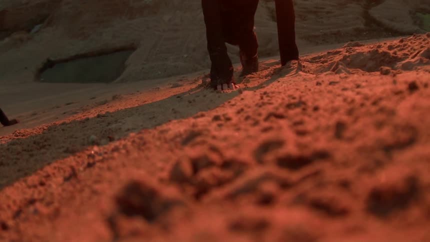 A person climbs up a dirt hillside