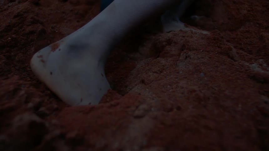A person is kicking around in the brown soil