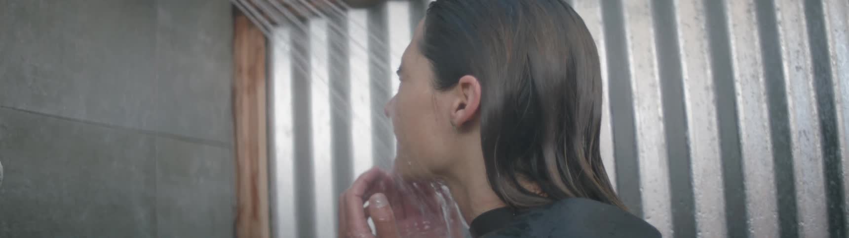 A woman wearing a wetsuit is showering down during the day