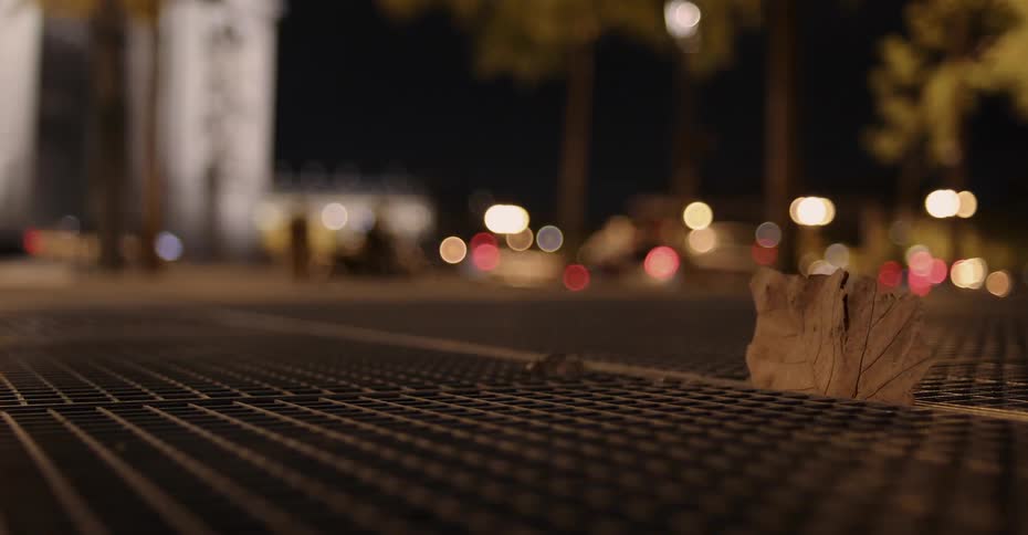 Paper stuck to a sewer grate blowing in the wind in the city at night