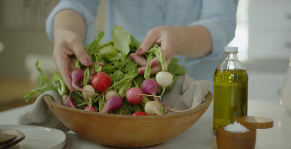 A woman arranges beats in a wood bowl
