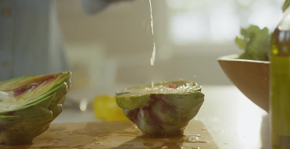 Person squeezes lemon juice onto artichokes