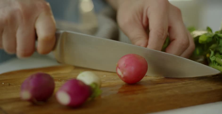 Person cuts the top off of a radish and places it next to three other radishes