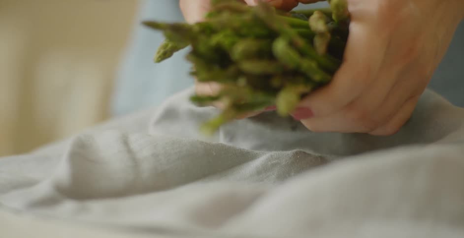 A woman picks up a bunch of asparagus that had been drying on a towel