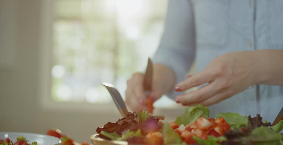 Someone is chopping strawberries for a salad