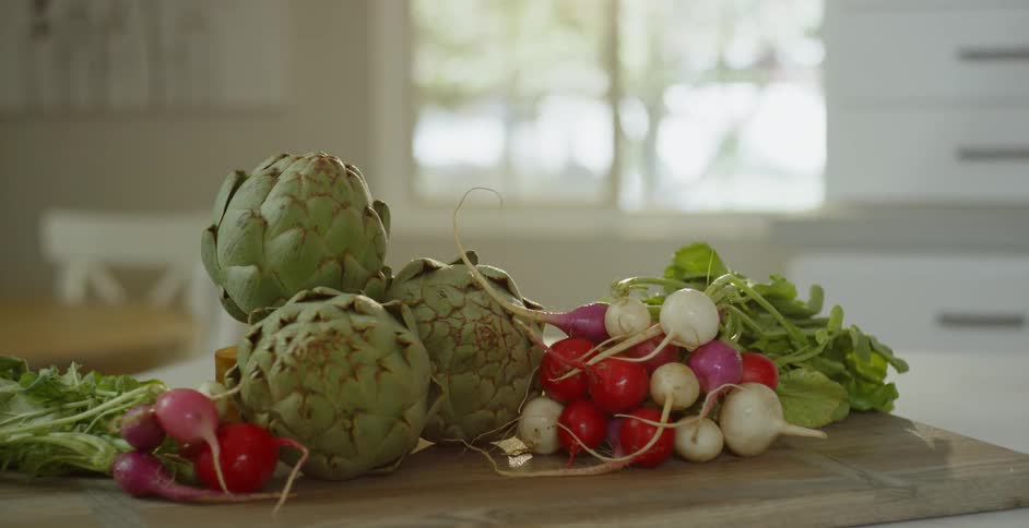 Artichokes and radishes sit on a cutting board