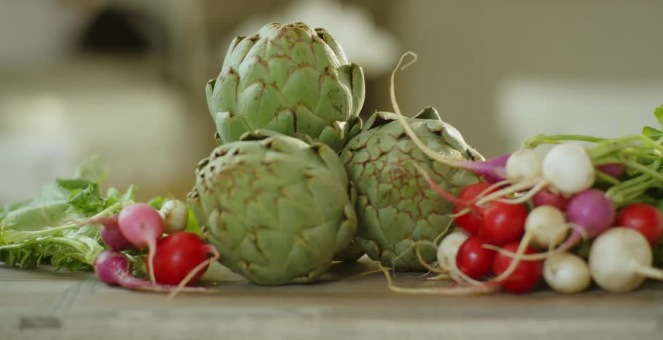 Artichokes and radishes sit on a cutting board