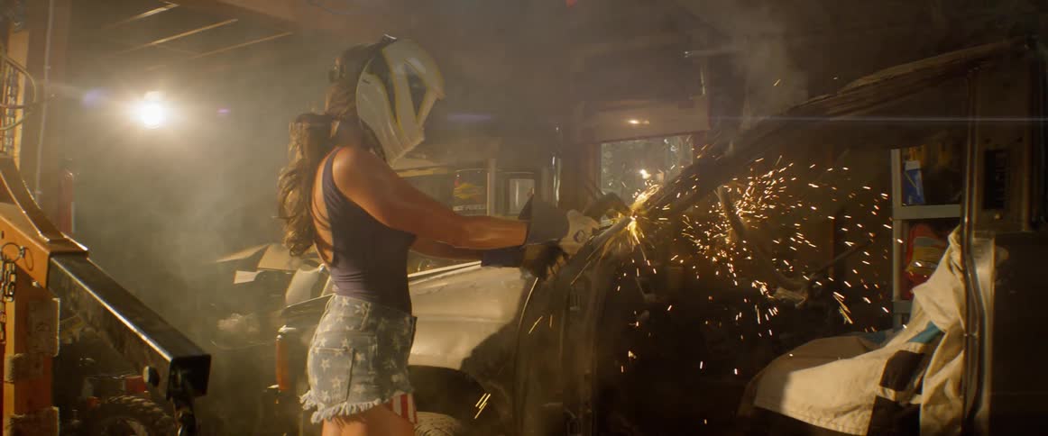 A woman welds a car in a garage