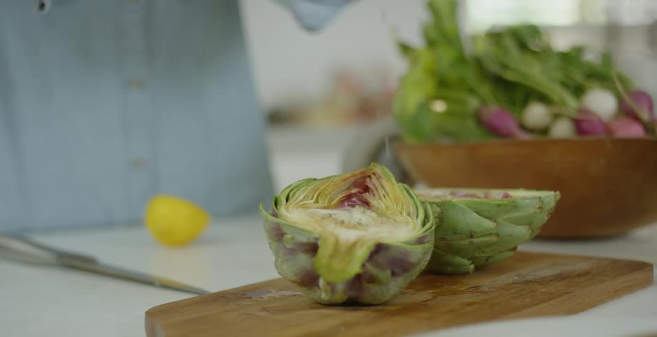 A woman sprinkles juice on vegetables placed on a cutting board