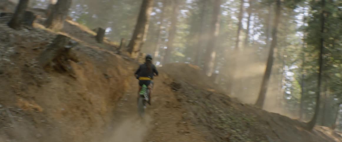A motorcyclist goes over a jump in a forest