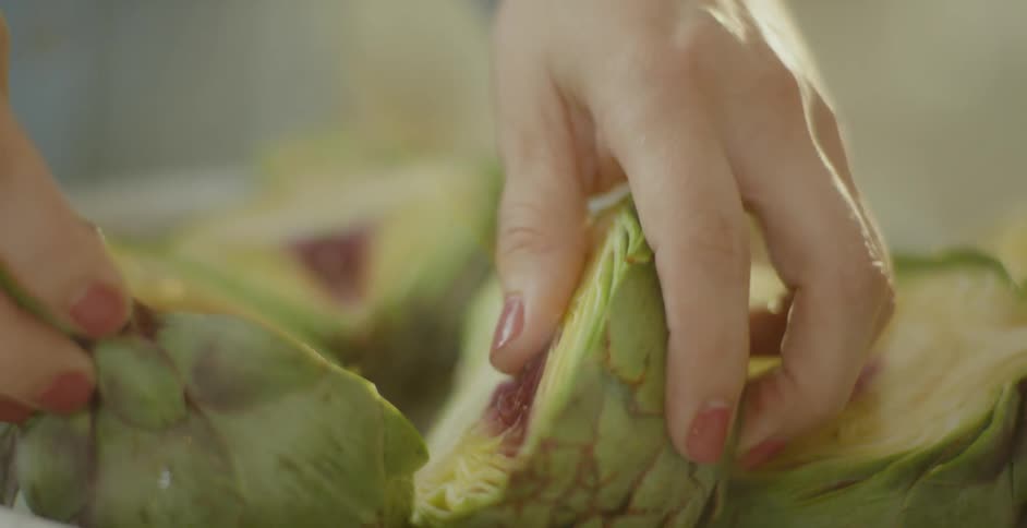 A woman arranges artichokes on a plate