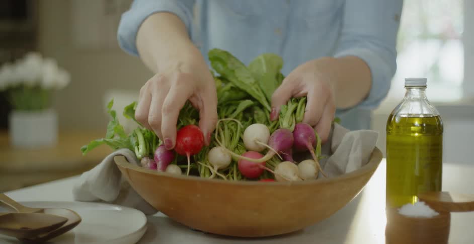 A woman puts beets in a wood bowl