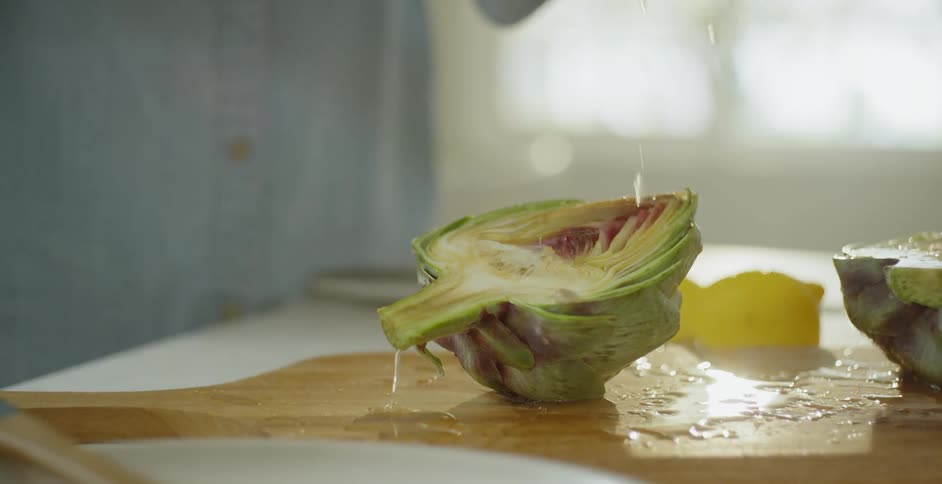Lemon juice is squeezed onto an artichoke