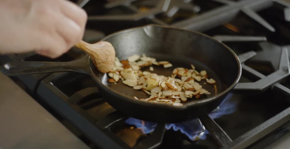 Person stirring their food in a skillet as it cooks on a gas stove