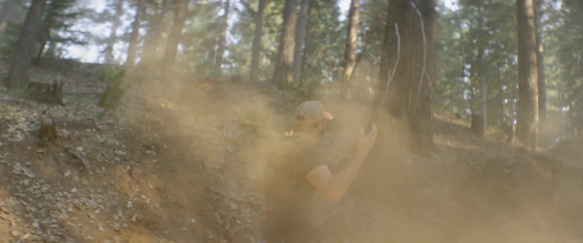 A motorcyclist goes over a jump in a forest