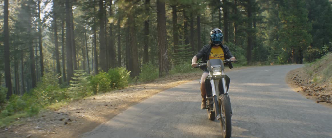 A motorcyclist rides through a forest