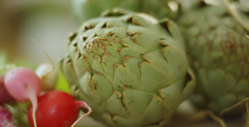 Artichokes and radishes sit on a cutting board