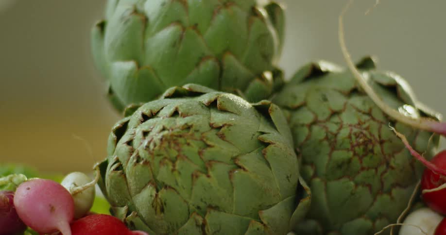 Artichokes and radishes sit on a cutting board