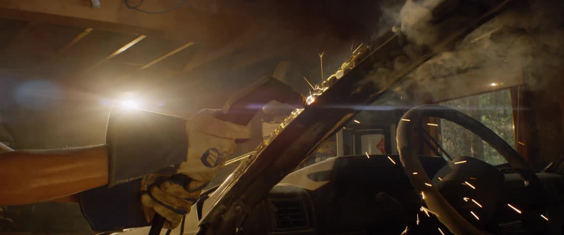 A woman welds a car in a garage