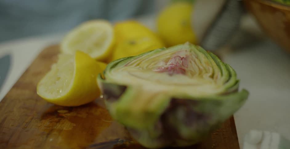 Several cut lemons and a cut artichoke on a cutting board