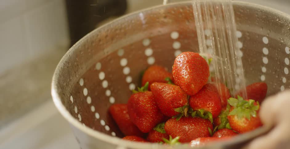 Strawberries are washed off in a colander