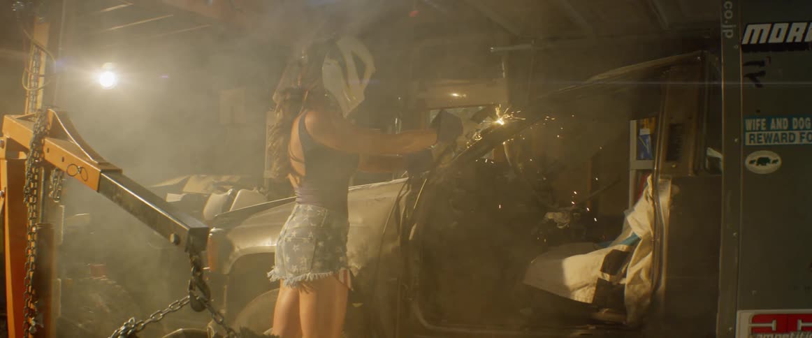 A woman welds a car in a garage