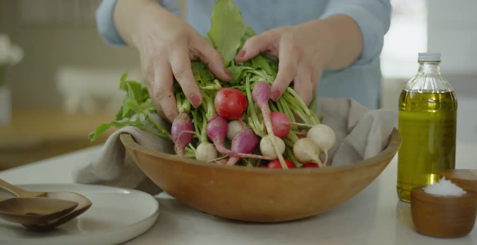 Person sets a bunch of red and white radishes in a bowl
