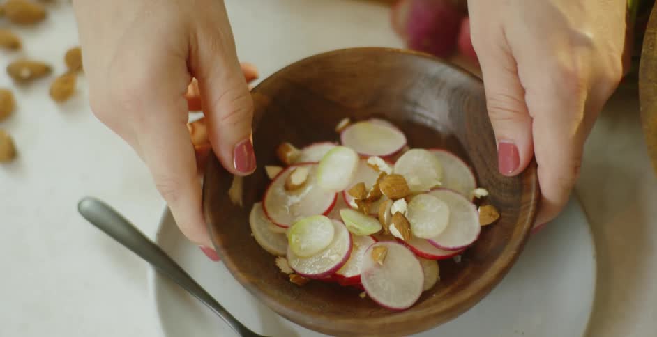 Woman lifts salad bowl from plate
