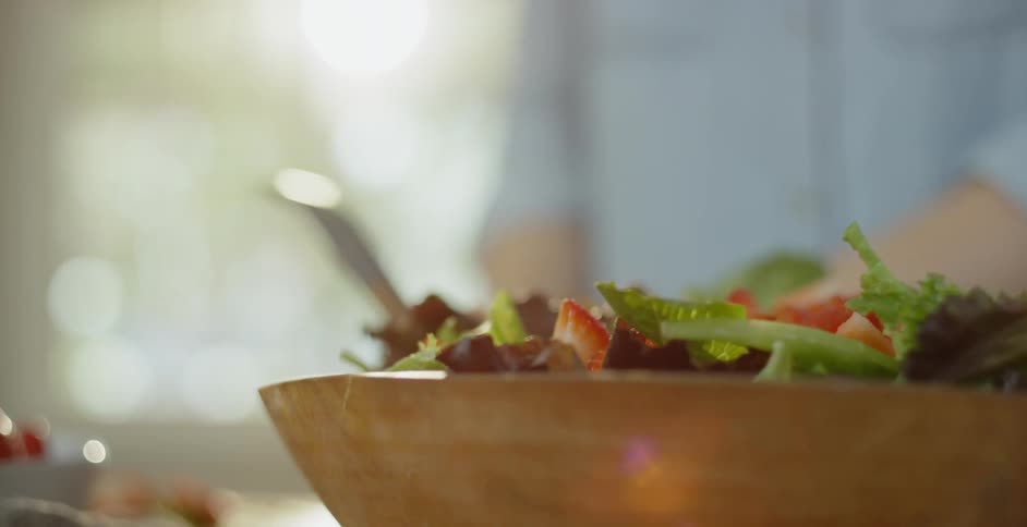A salad is put together in a wood bowl