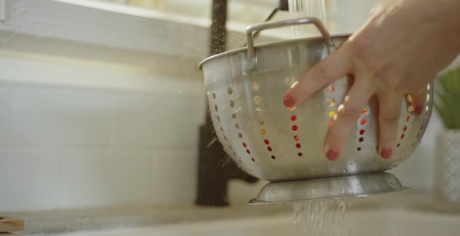 A woman washes off produce in the sink